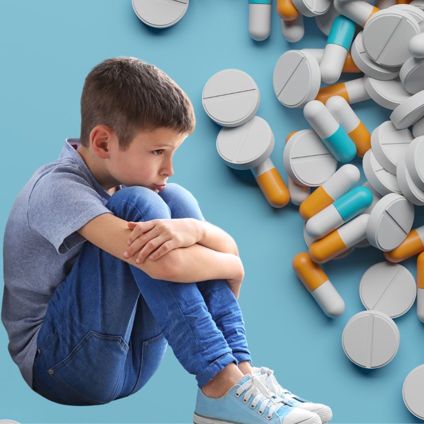 a boy sitting on the floor next to a pile of pills
